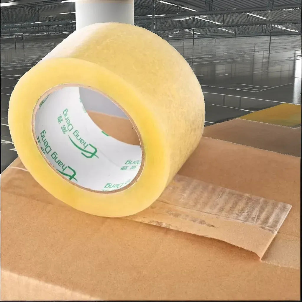 Transparent yellow packing tape roll applying to carton seam, pressure sensitive waterproof