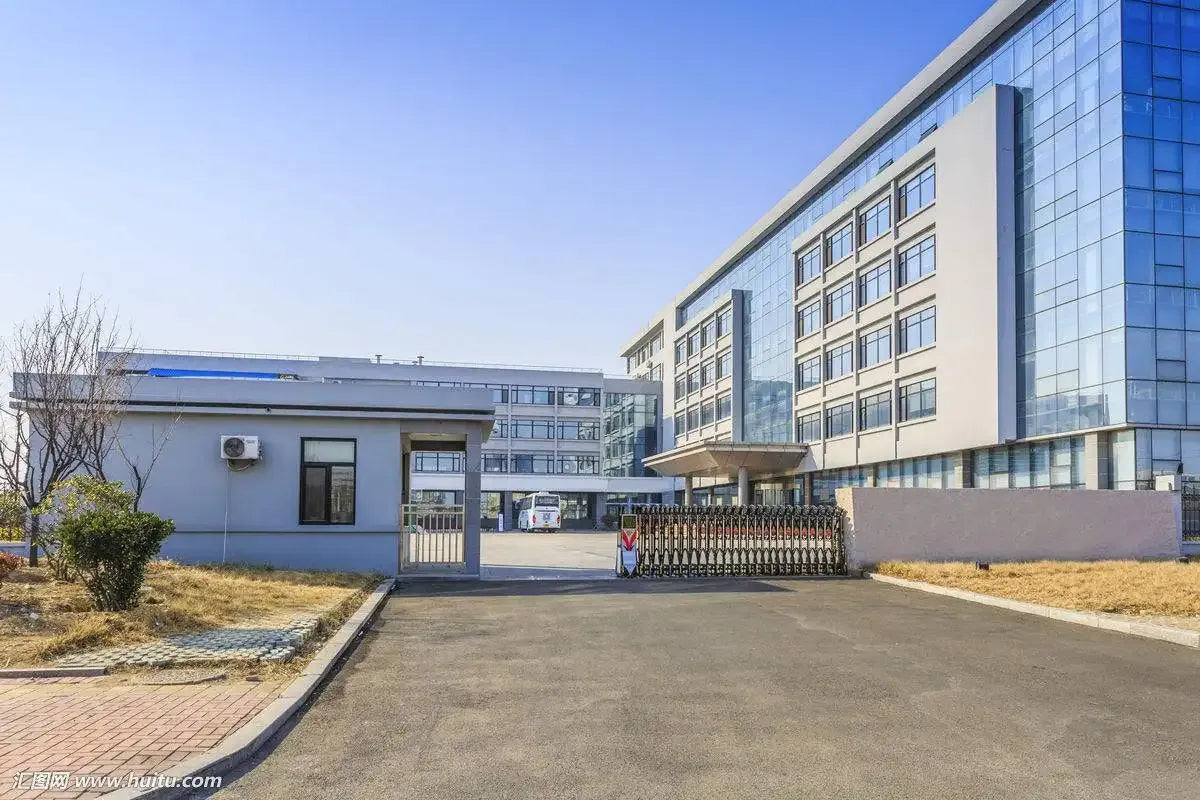 Industrial facility building exterior with paved driveway and fenced courtyard