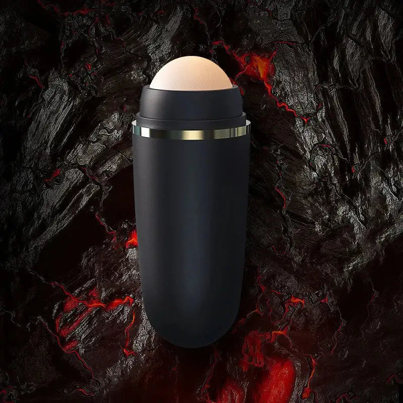 Matte black volcanic stone facial oil-absorbing roller with a gold ring, set against a dark lava-textured background.