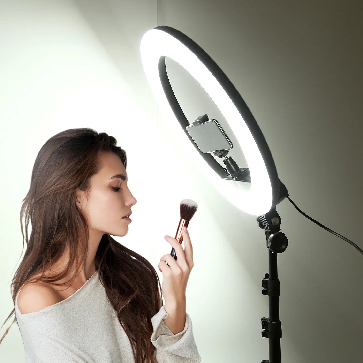 Large circular LED ring light on a black tripod stand with a centered smartphone mount for content creation.