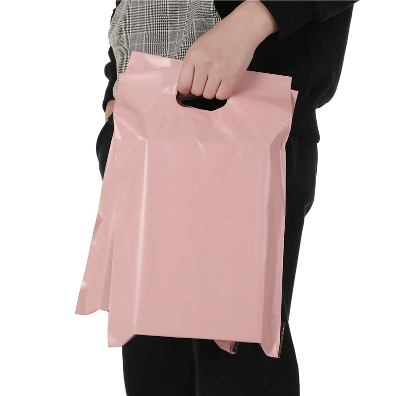 Pink plastic mailing bag held by hand with gusseted fold and open top