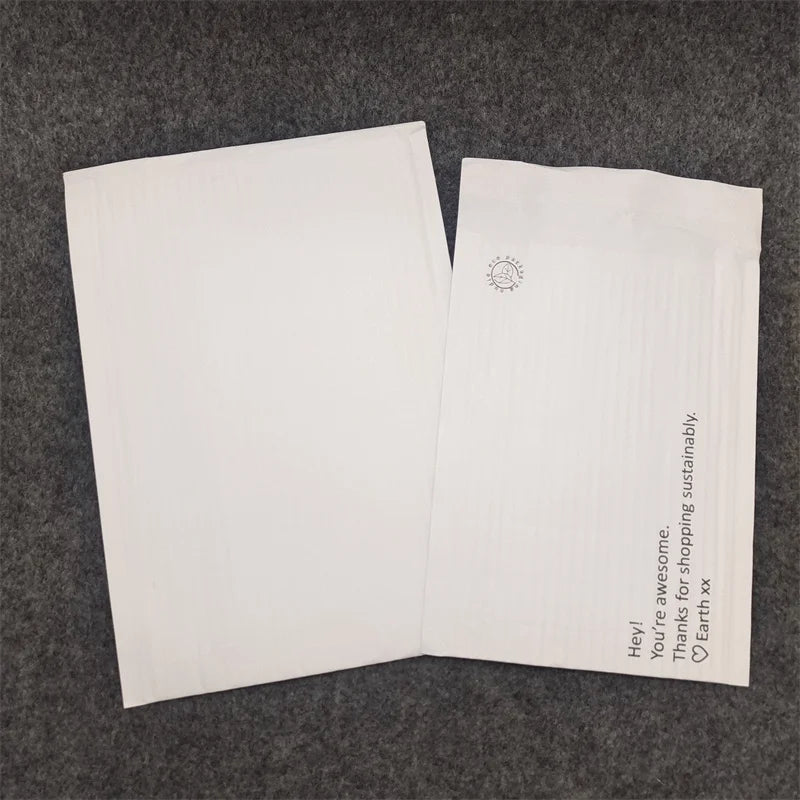 Pair of white padded shipping mailer bags with small icons and vertical text