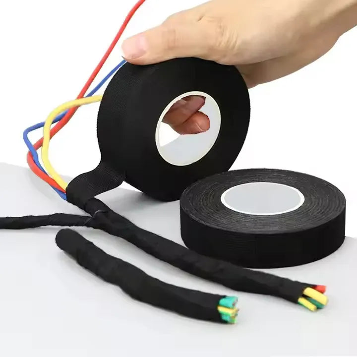 Black wire harness tape roll and extra tape strip on a white surface