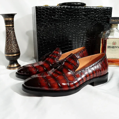 Luxury burgundy crocodile leather tassel loafers with black soles for men.