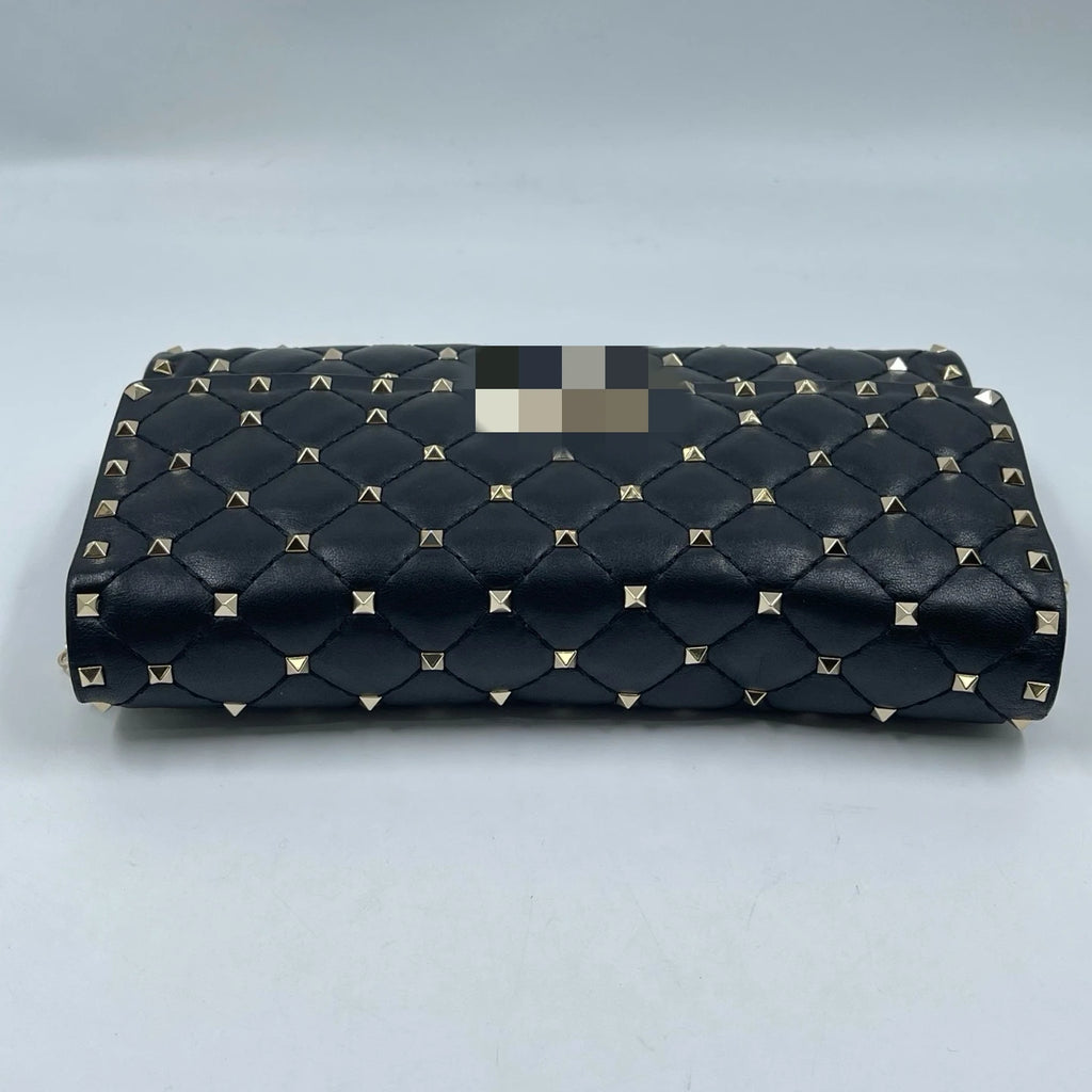 Luxury black quilted leather designer handbag with gold-tone pyramid rivets, rectangular shoulder bag style.