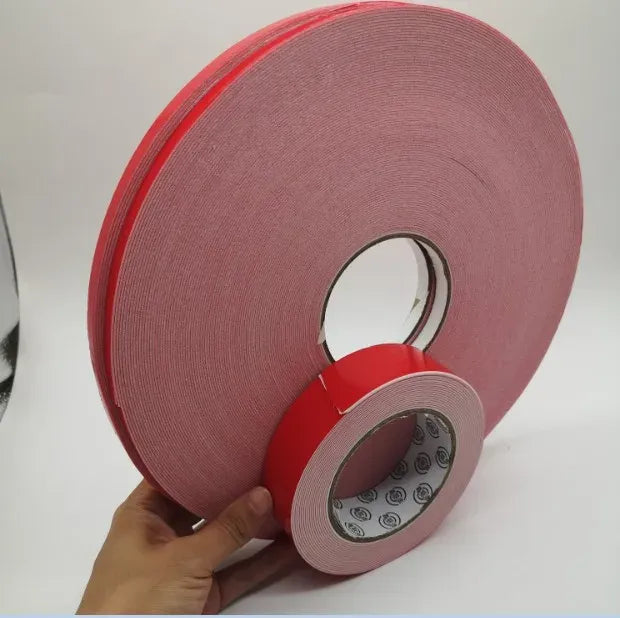Double-sided heat resistant foam adhesive tape roll, red, held near a circular liner