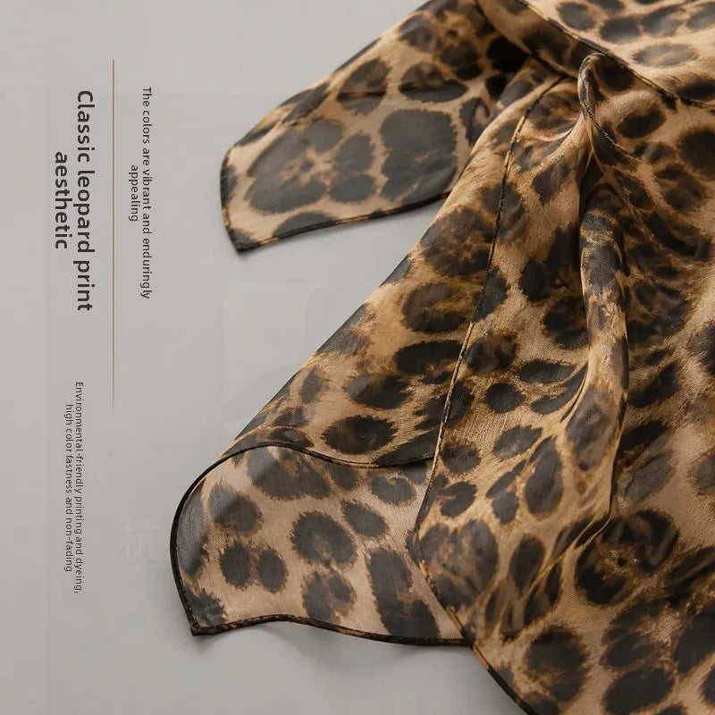 Luxury brown leopard print silk scarf with long, flowing shape and soft, vibrant aesthetic.