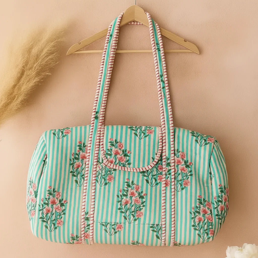 Vintage-style light green striped weekender duffle bag with pink floral print, quilted cotton fabric, and long straps.