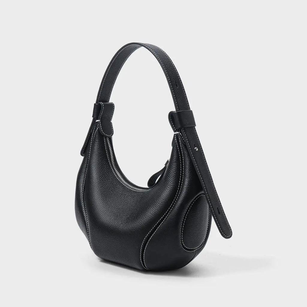 Black pebbled leather half moon handbag with white contrast stitching, shoulder strap, and top zipper.