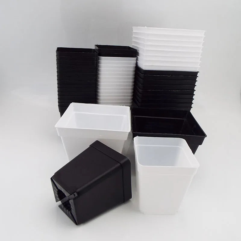 Mixed mini plastic square planter pots in black and white, stacked with lids