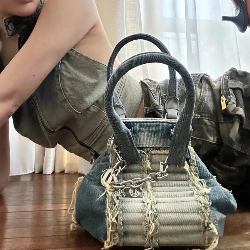 Vintage washed blue denim hobo handbag with frayed edges, quilted panel, and silver chain detail. Luxury casual trunk.