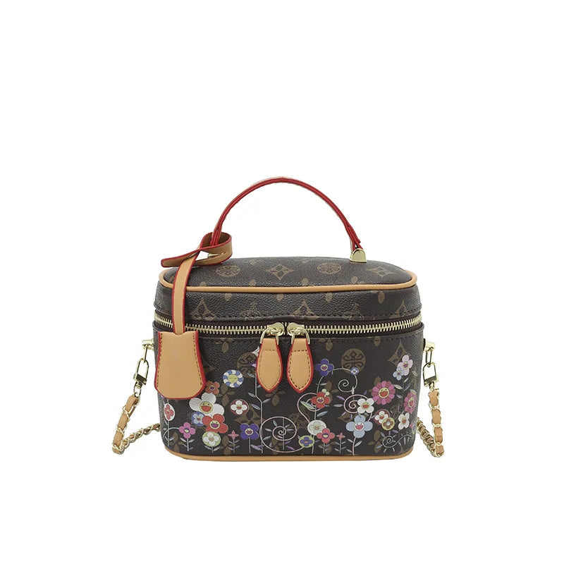 Luxury brown cowhide leather trunk vanity bag with multi-color flower monogram, red handle, and gold chain strap.