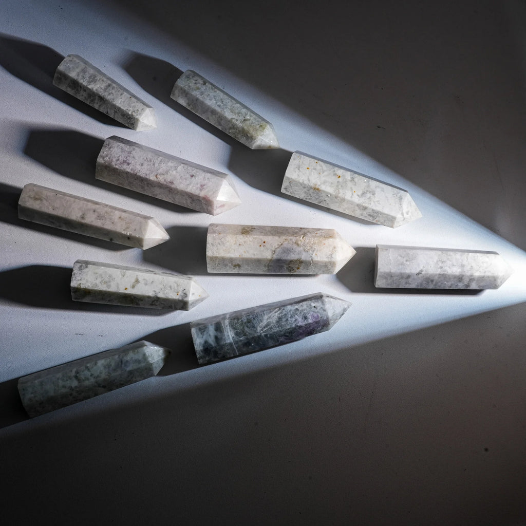 Natural gemstone crystal point tower pieces laid in a row with pointed ends.