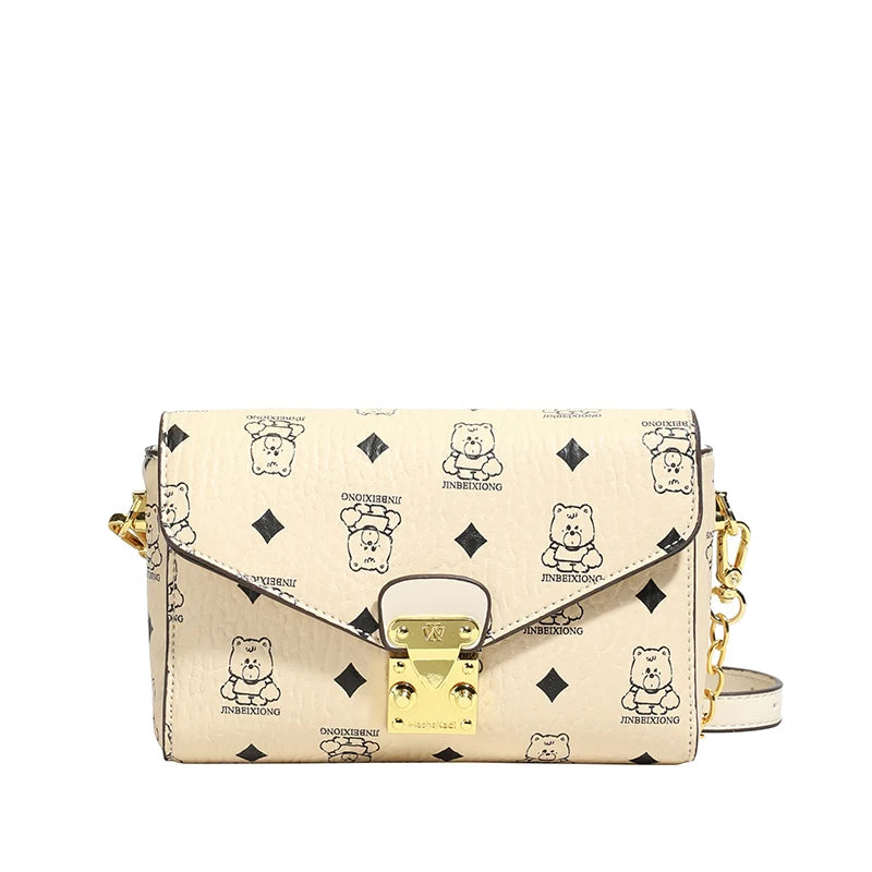 Cream monogram leather envelope crossbody bag with bear print, gold hardware, and chain shoulder strap. Trunk style.