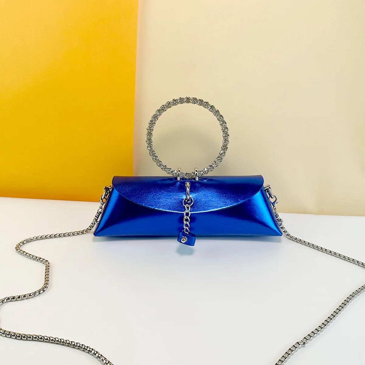 Metallic blue PU leather evening clutch with crystal ring handle, chain strap, and elegant wedding trunk design.