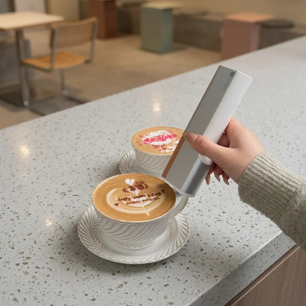 Handheld coffee inkjet printer in white, printing a latte foam design