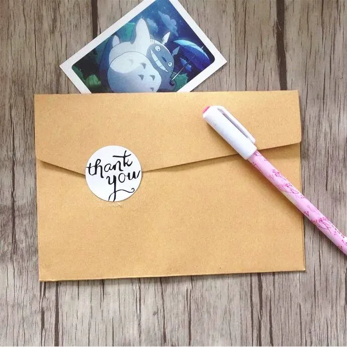 Brown kraft envelope with a round white “thank you” adhesive seal sticker.