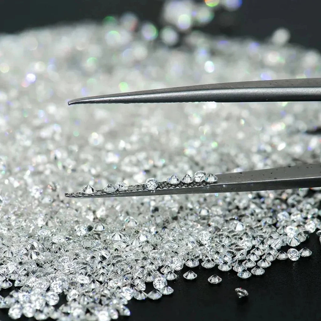 Loose round brilliant lab-grown diamonds scattered, shown with metal tweezers