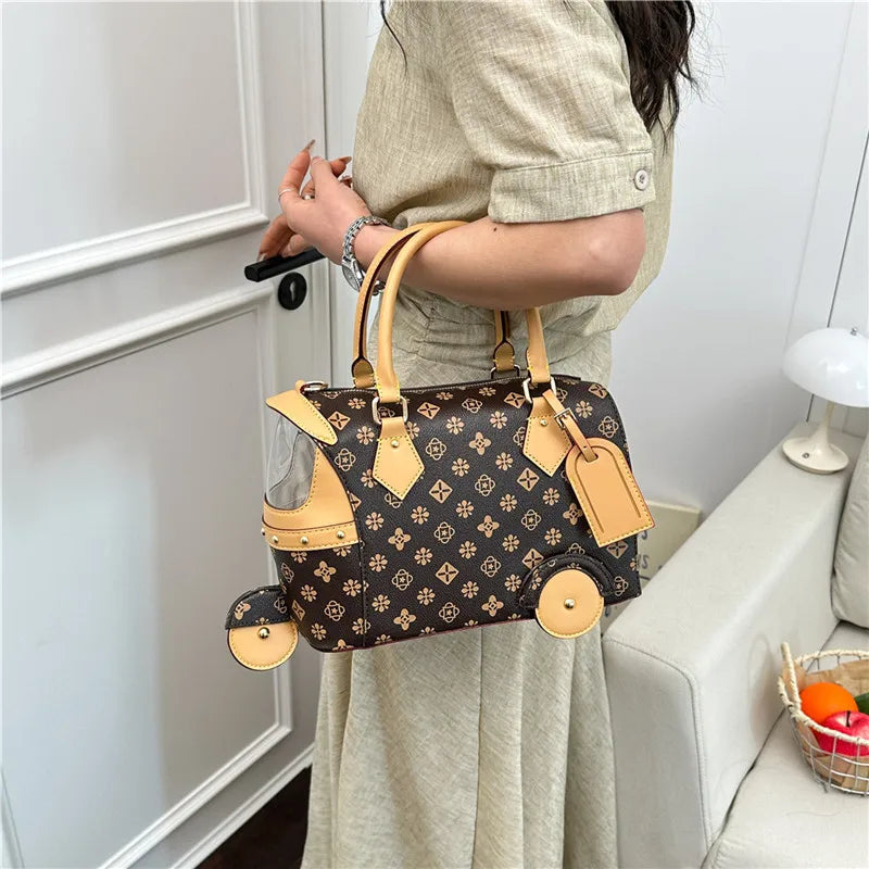 Brown PU leather trunk handbag with floral print, light tan accents, and whimsical tricycle wheel detailing.