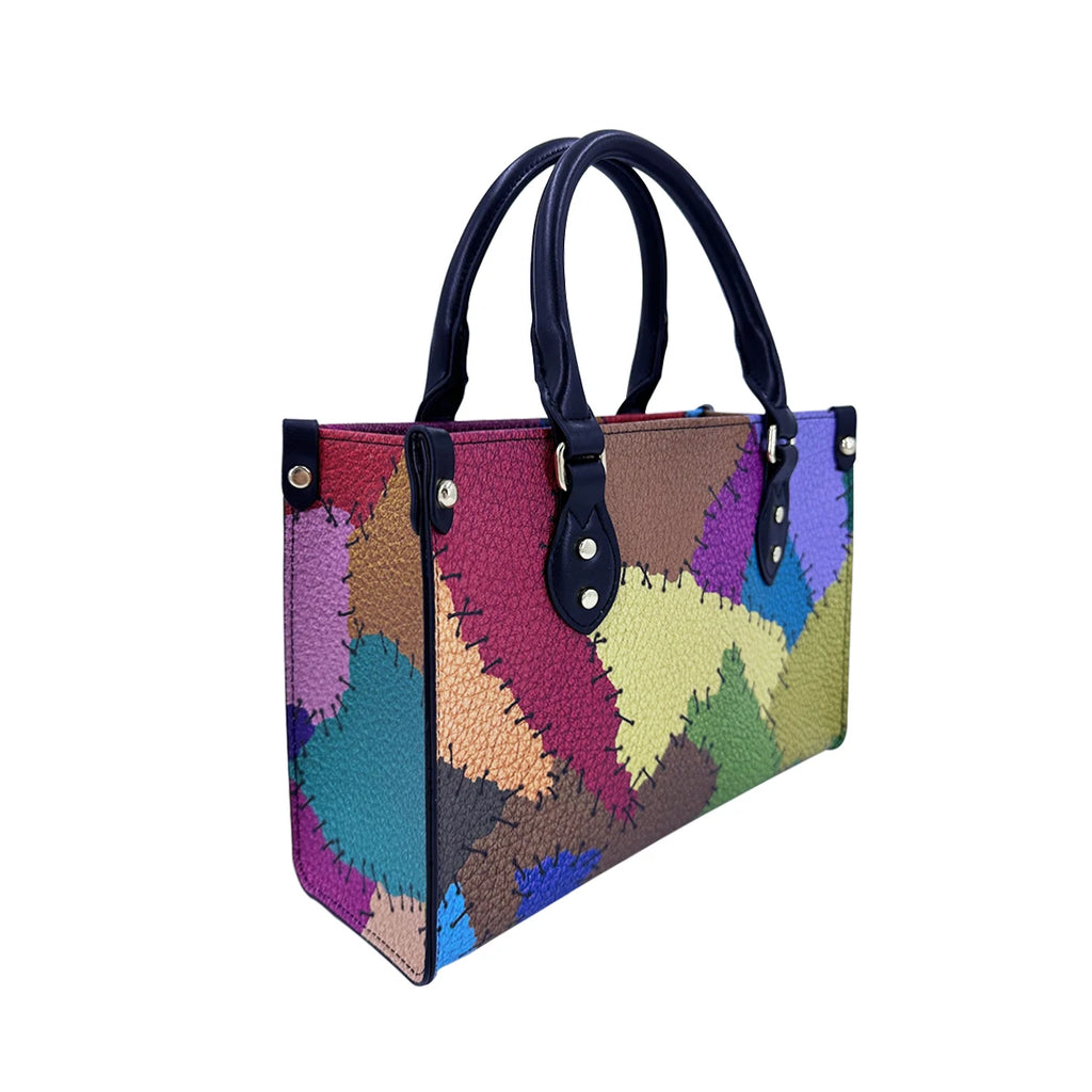 Multicolor PU leather patchwork handbag with trunk-style boxy frame, navy handles, and decorative stitched accents.