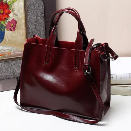 Luxury maroon genuine leather handbag, classic tote style with dual top handles and detachable shoulder strap.