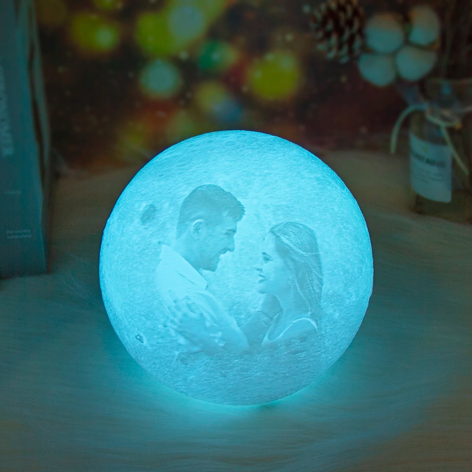 Custom photo moon lamp. Textured, spherical bedside night light glowing with a soft blue hue and couple portrait.