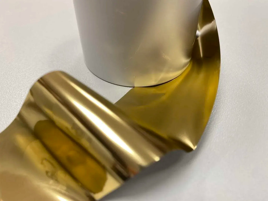 Shiny gold metallic printer ribbon, close-up of foil web on a roll.