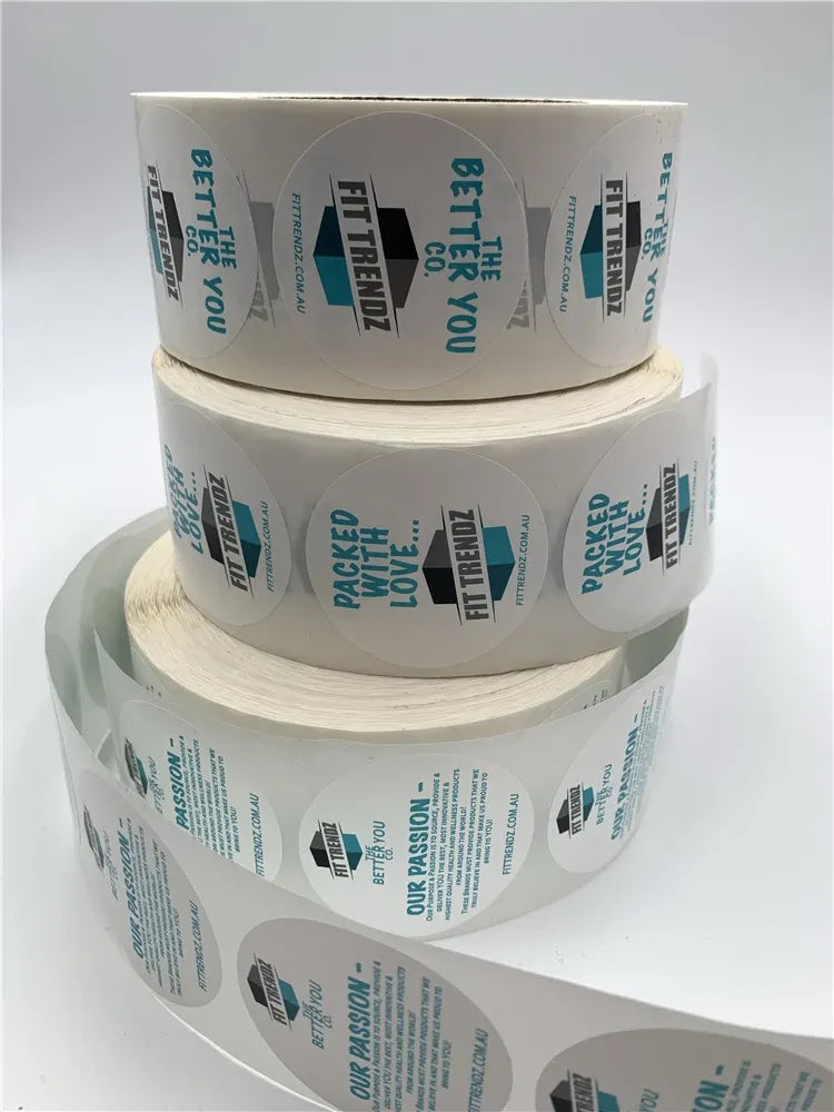 Stack of white custom printed packaging label sticker rolls with blue text