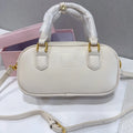 Cream leather trunk handbag with gold hardware, top handles, and adjustable crossbody strap. Luxury designer style.