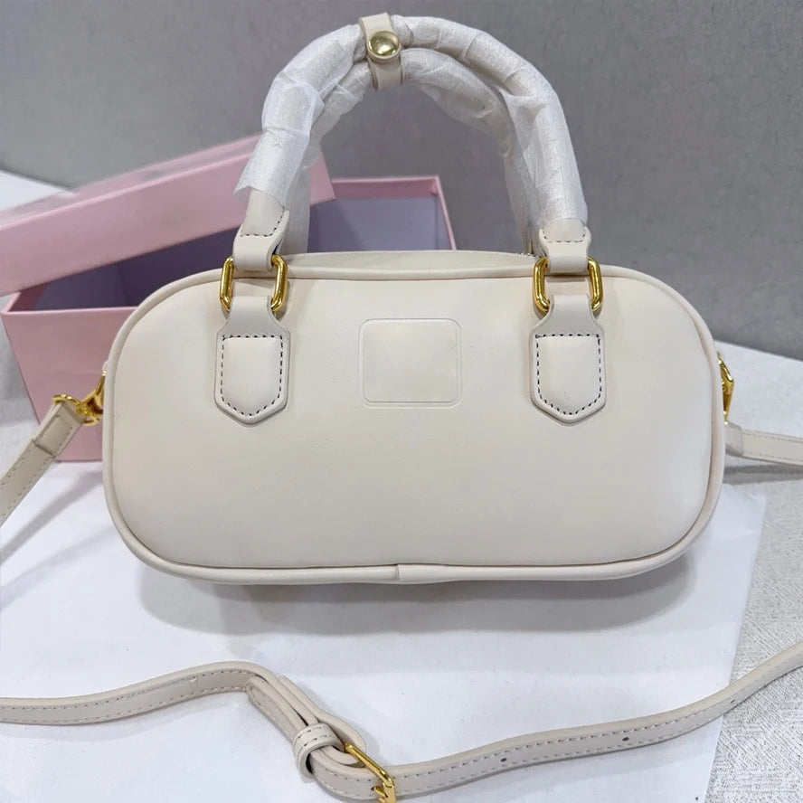 Cream leather trunk handbag with gold hardware, top handles, and adjustable crossbody strap. Luxury designer style.
