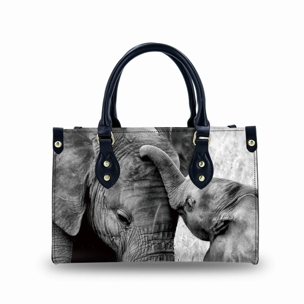 Genuine leather trunk handbag featuring a black and white elephant trunk print, black top handles, and buckle details.