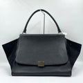 Classic black designer shoulder bag in lychee texture leather with vintage swing side panels and a single top handle.