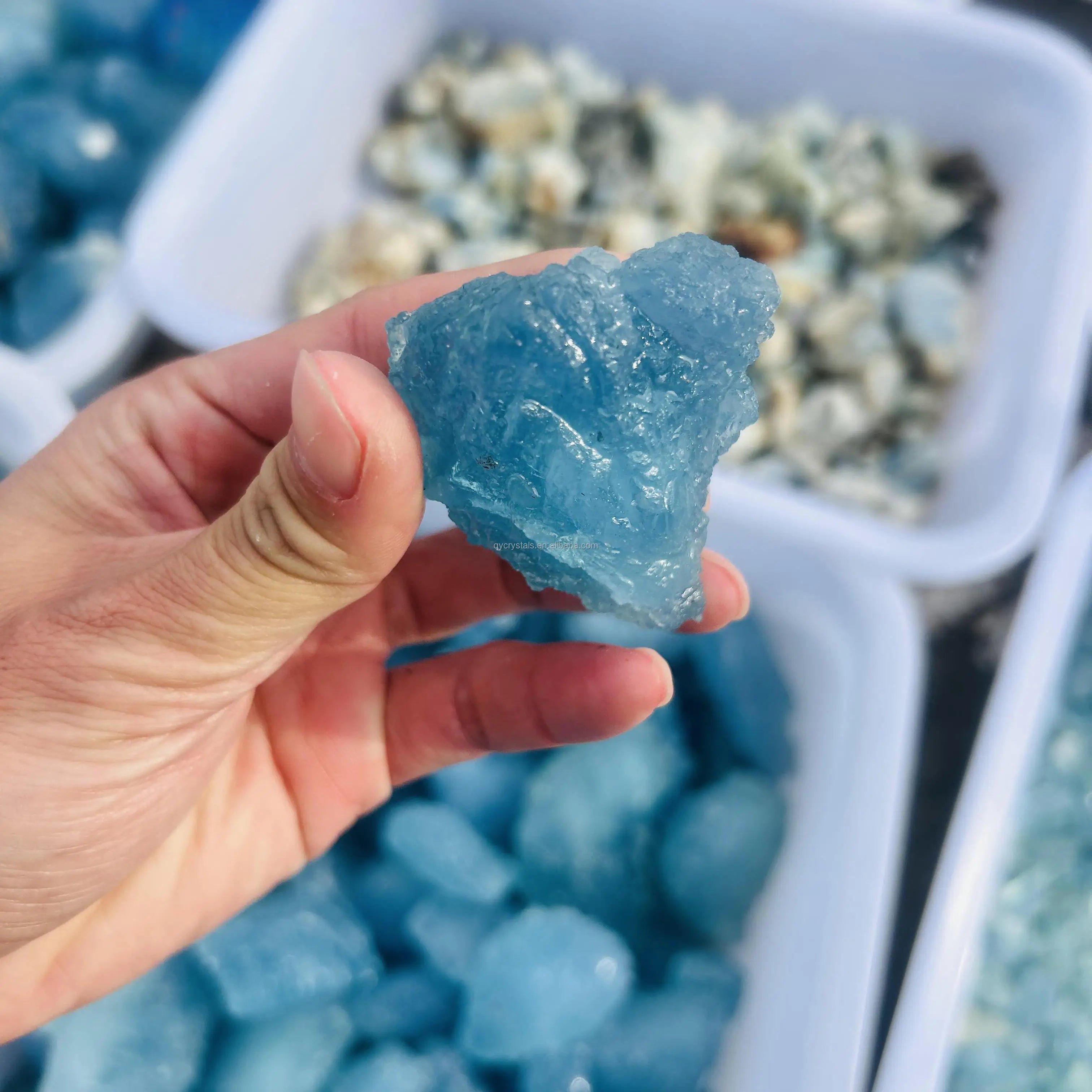 Sky blue aquamarine rough crystal stone, pointed edge, held in hand