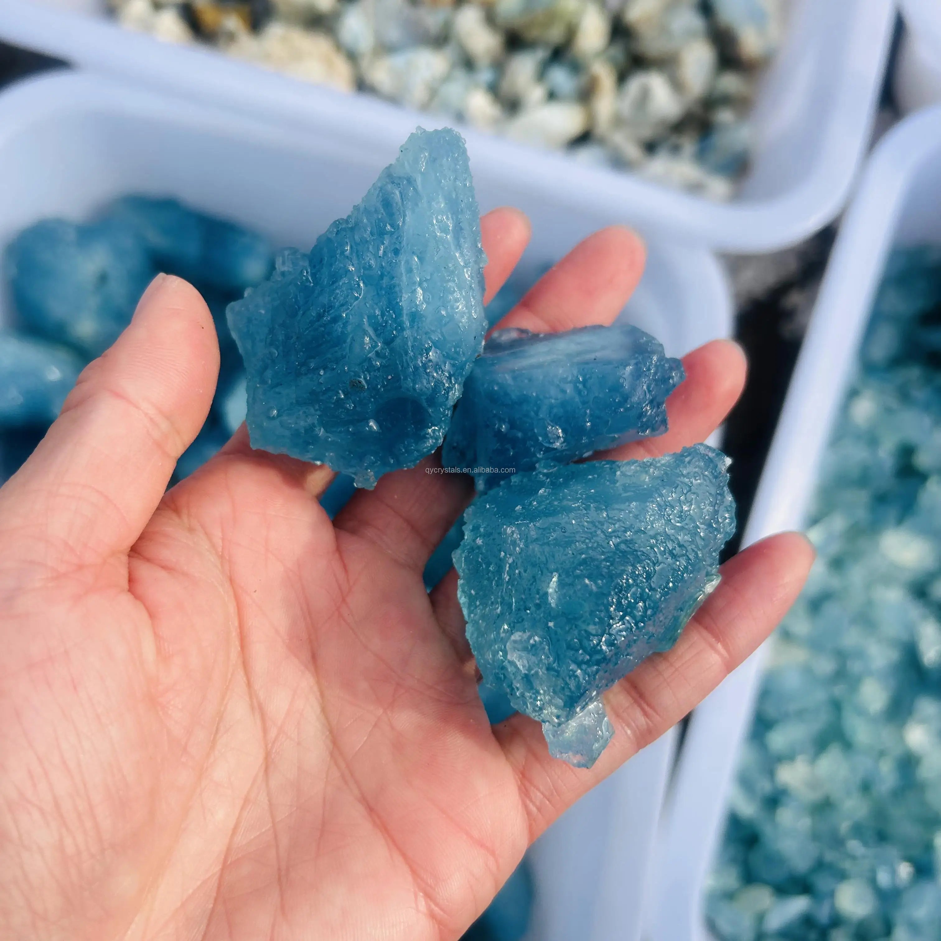 Three sky blue aquamarine rough crystal stones, jagged pieces in hand