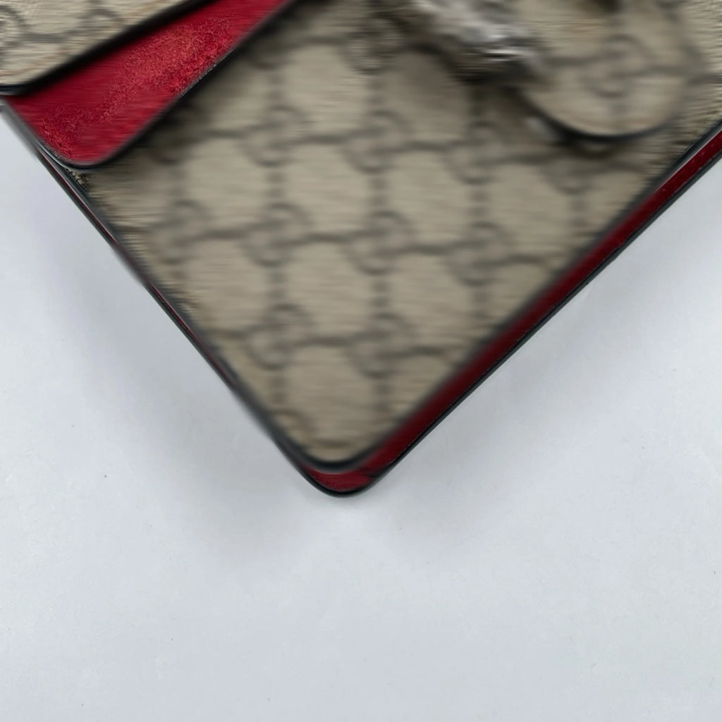 Pre-owned designer shoulder bag in beige canvas with vintage logo pattern and vibrant red suede trim.