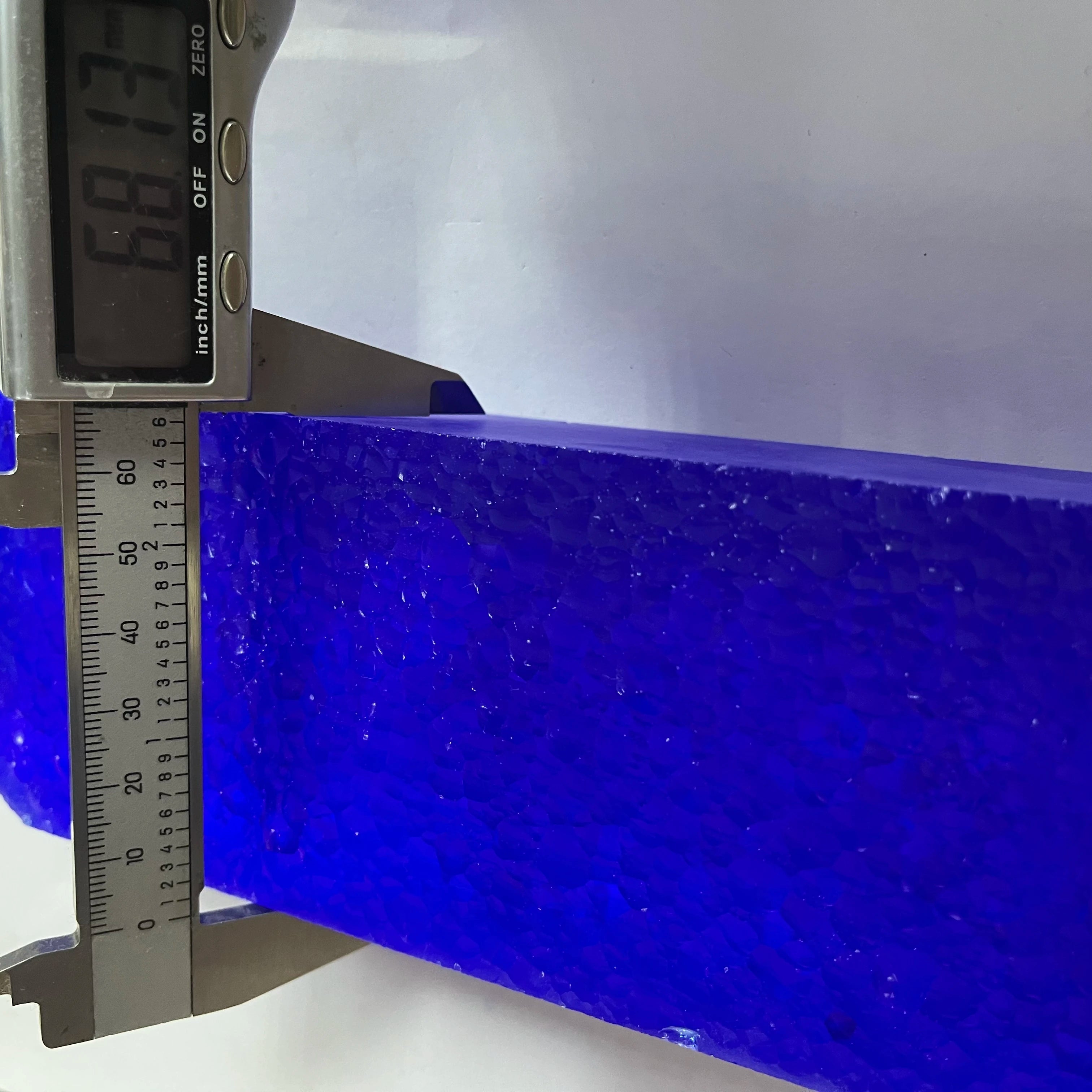 Blue synthetic hydrothermal crystal block with ruler measuring width and length.