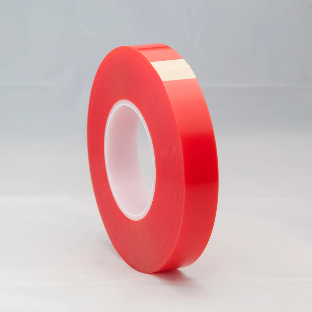 Red double-sided tape roll on its edge with white inner opening