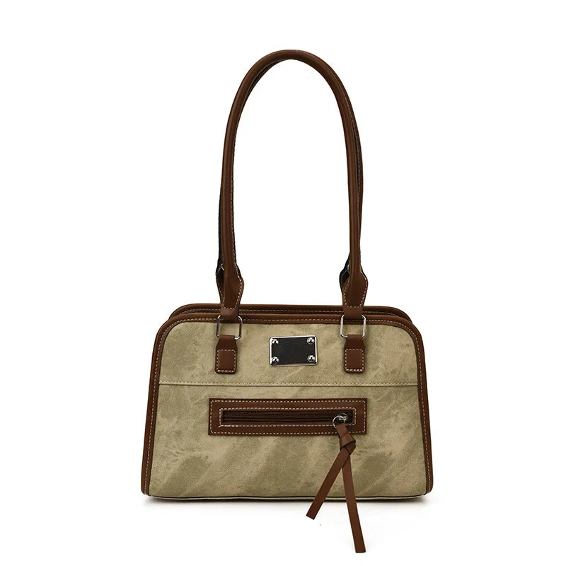 Beige and brown soft leather trunk tote bag with shoulder straps, front zipper pocket, and metallic brand logo plate.