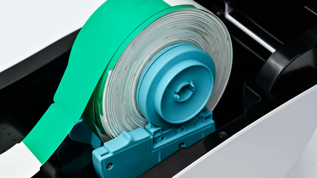 Close-up of label roll and green print media path inside a direct thermal printer.