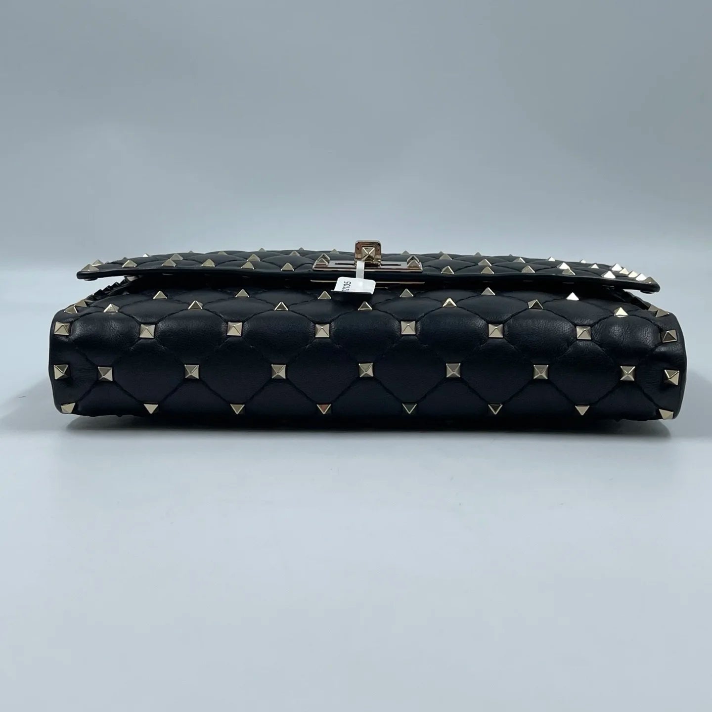 Pre-owned black quilted leather designer handbag with gold pyramid rivets and a turn-lock closure.