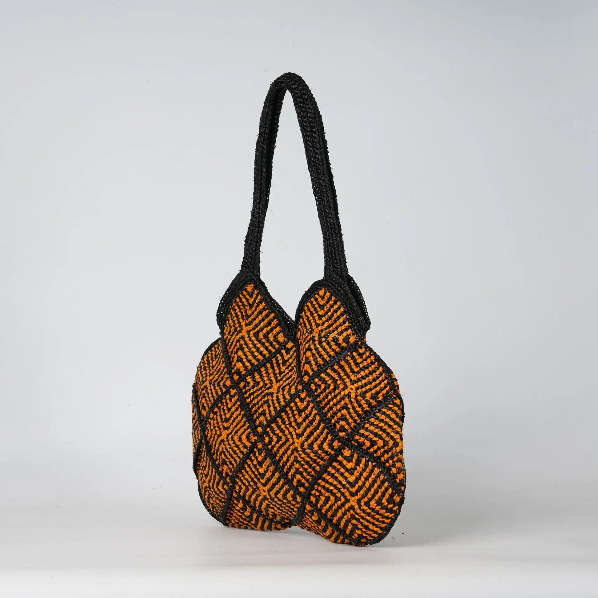 Boho black and orange crochet tote bag with geometric diamond patterns and sturdy woven handles for summer beach use.