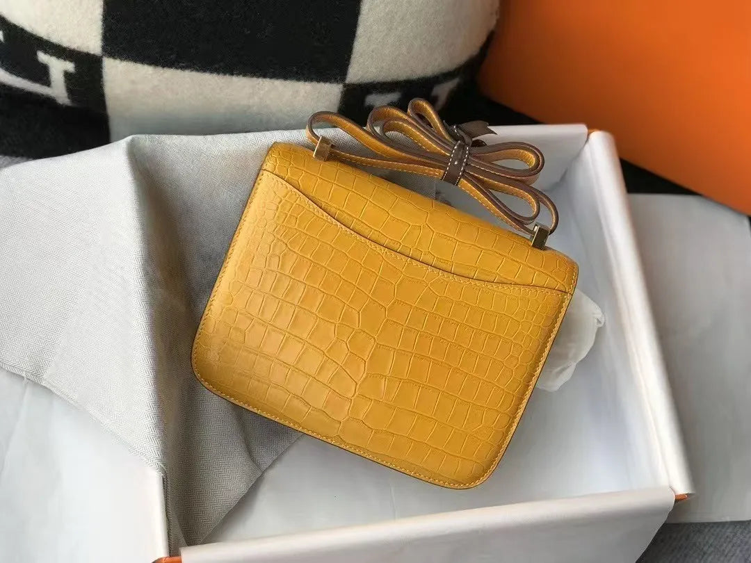 Yellow alligator-pattern leather shoulder bag with slim strap in a branded gift box. High-end trunk style accessory.