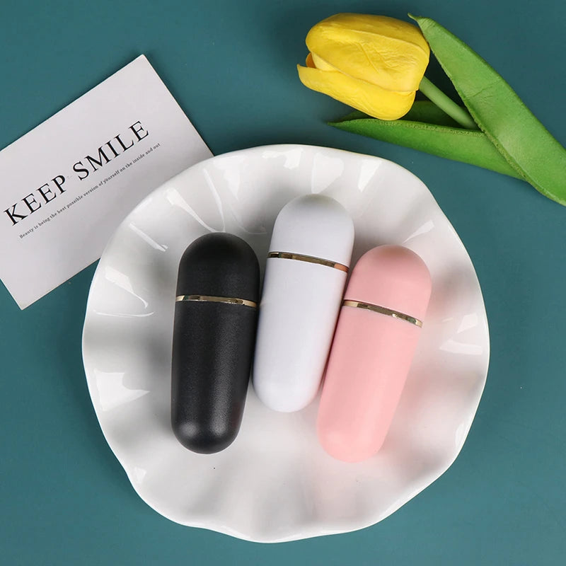 Three oil-absorbing volcanic stone rollers in black, white, and pink, on a white plate with a yellow tulip.