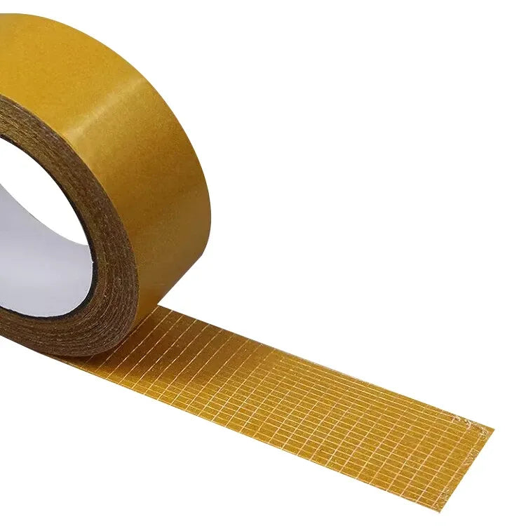 Tan-brown double-sided tape strip on grid liner, close-up of adhesive edge