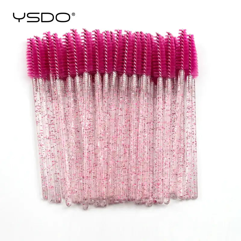Disposable eyelash brushes with hot pink bristles and clear plastic handles embedded with pink glitter.