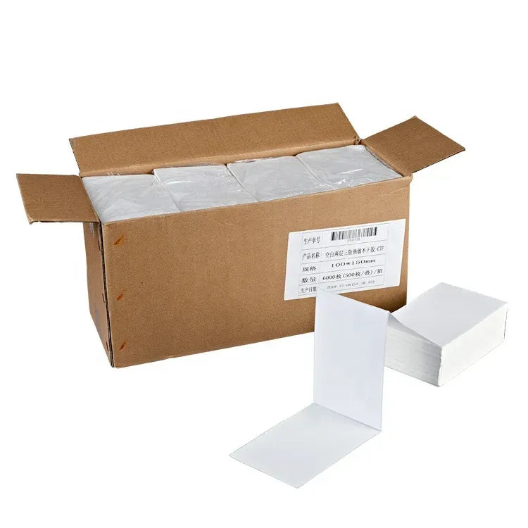 White thermal shipping labels in a fanfold stack with a shipping carton nearby