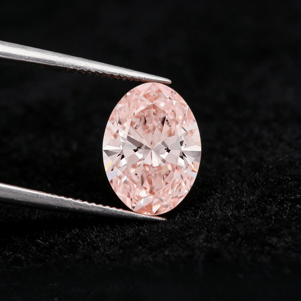 Oval fancy pink lab-grown diamond held in metal tweezers, visible facet pattern
