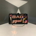 Black rhinestone crystal clutch with "BAD gyal" text, makeup brush, and lip motif. Glamorous evening designer handbag.