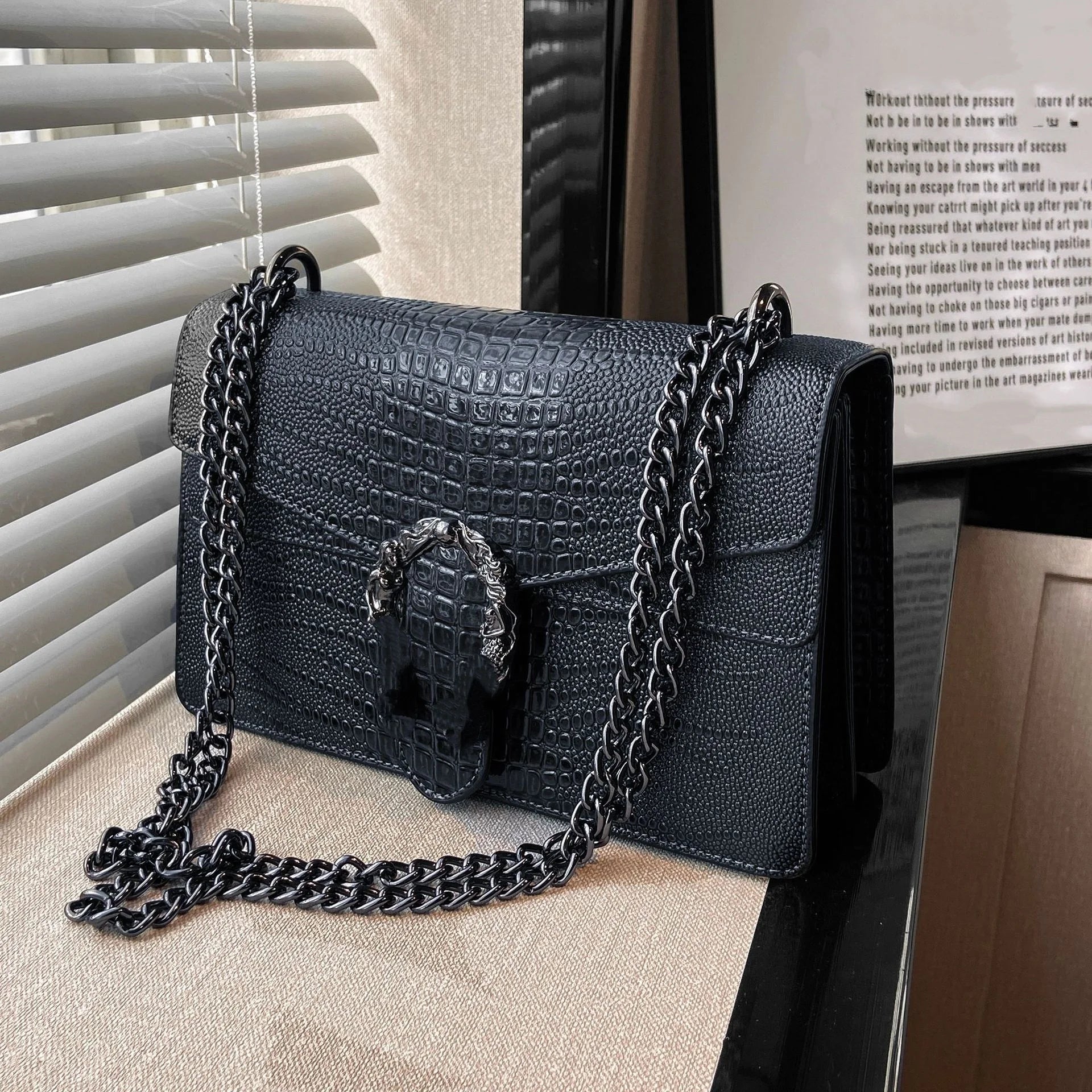 Black luxury crocodile-pattern crossbody trunk bag with a metallic horseshoe clasp and chain shoulder strap.