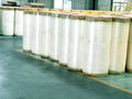 BOPP adhesive tape jumbo rolls, multiple clear white rolls lined up on warehouse floor
